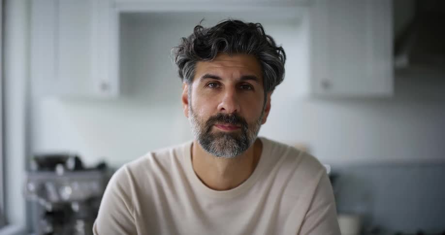 A man is sitting at home in his kitchen