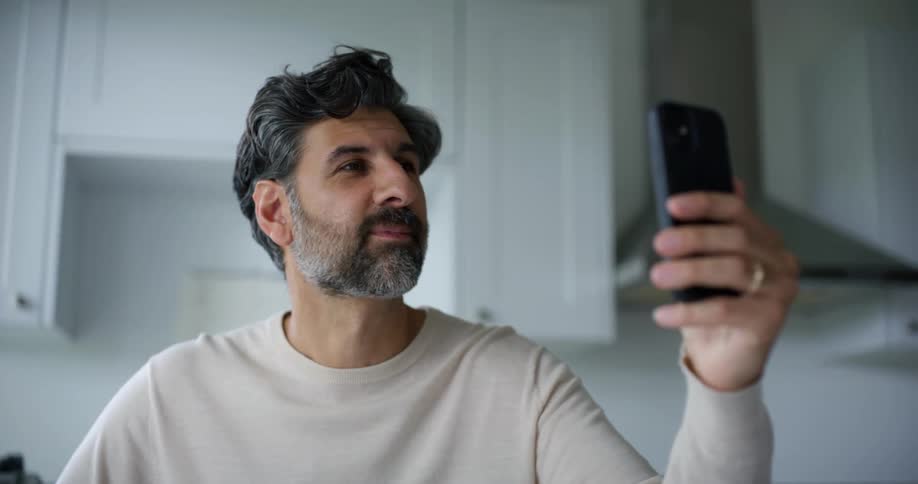 Man in kitchen talking on video call on smartphone