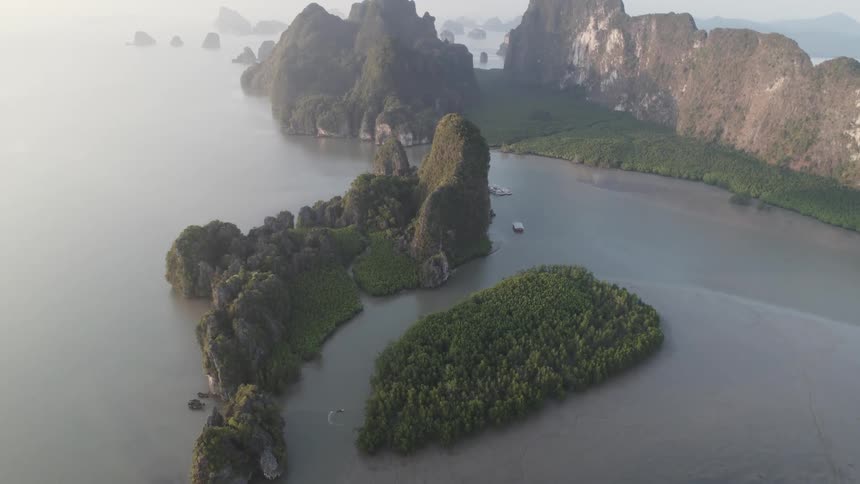A winding bay cuts through a landscape of dramatic limestone cliffs with boats traveling along its waters
