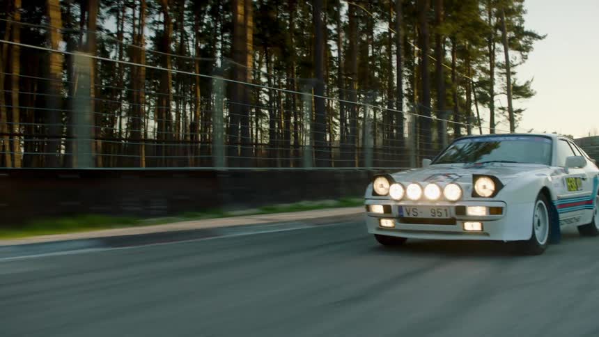 A rallyspec porsche 911 drives through a deserted race track at dusk