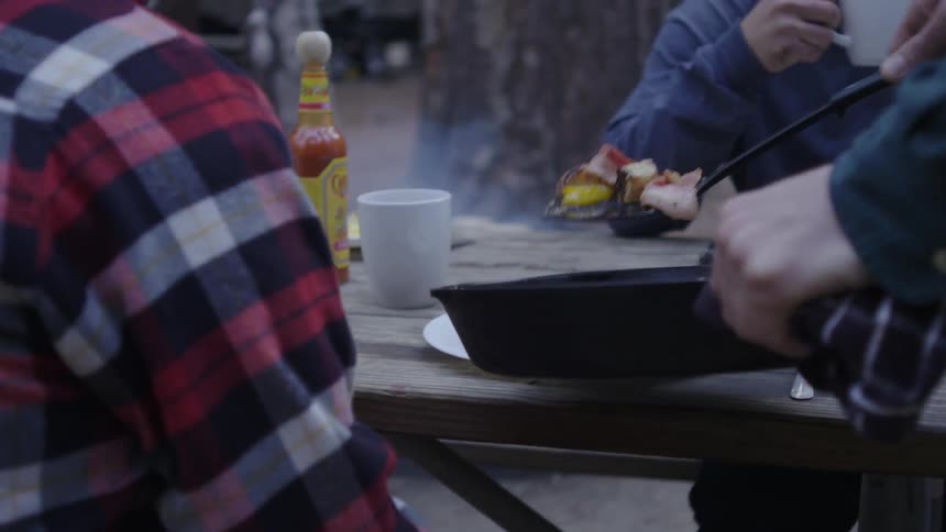 Campers gather at a picnic table to eat breakfast