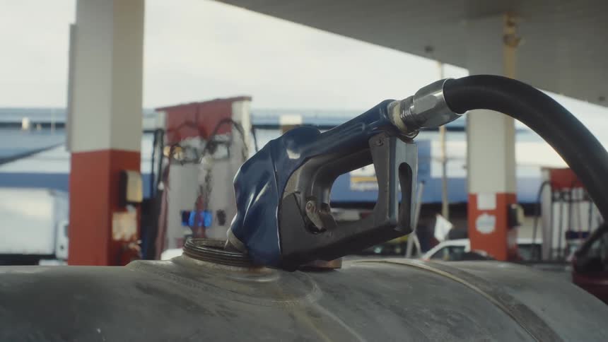 Blue fuel pump connected to a metal tank at a gas station