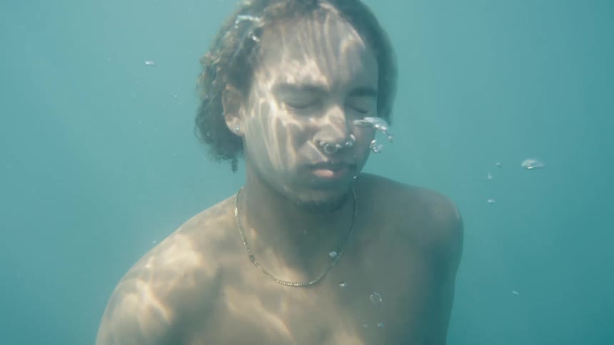 Man diving into an ocean with air bubbles rising