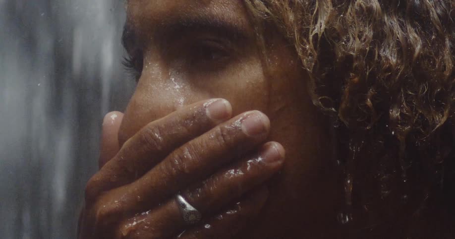 Man running his hand over his face with water falling