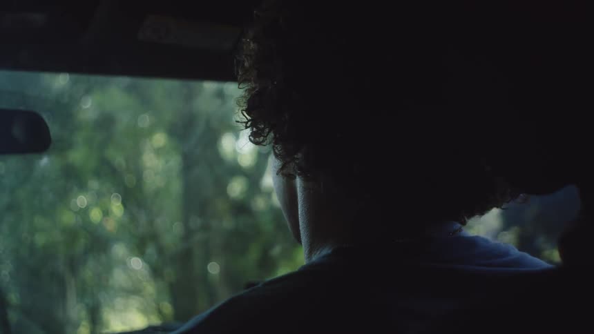 Man wearing sunglasses sitting in the front seat of a moving vehicle