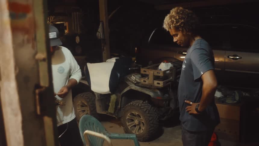 Two people are organizing cables inside a garage with an atv and a car parked nearby