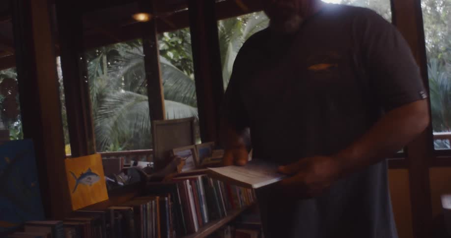 Man picking up a book and sitting down