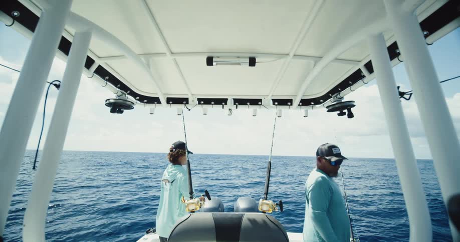 Two fishermen in a boat at sea during a partly cloudy day