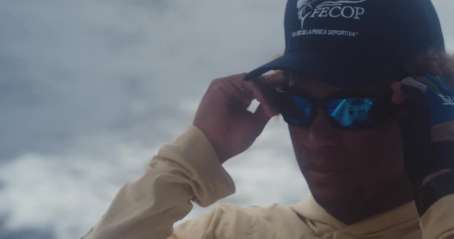 Portrait of a young man putting on sunglasses while on a moving boat