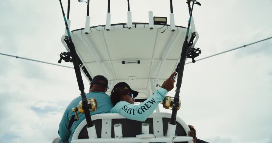 Two men fish on a large boat on a cloudy day