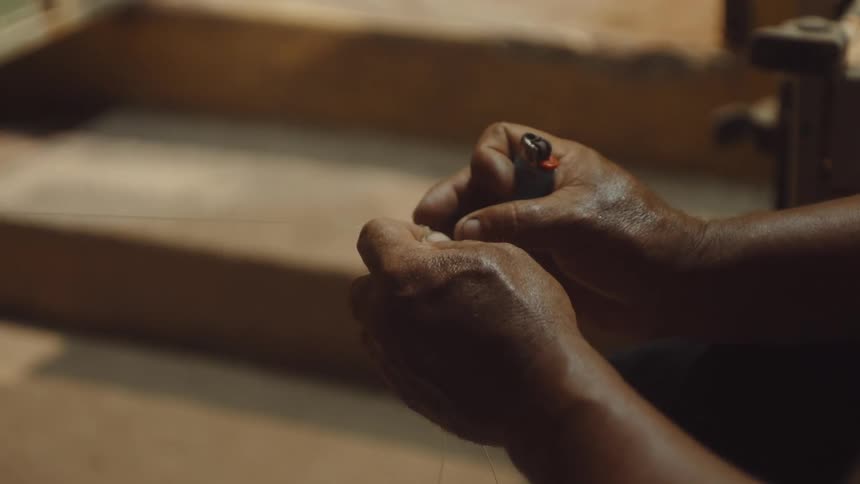 A man uses a lighter on a wire