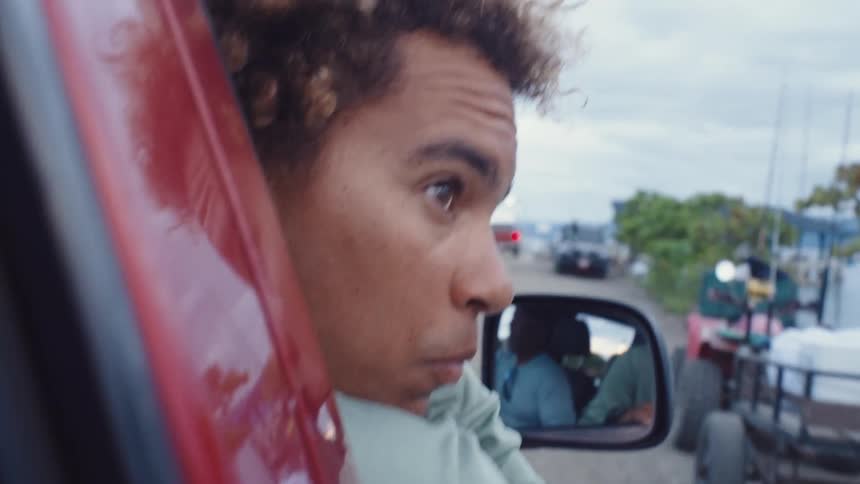 A mans head hangs out the moving car