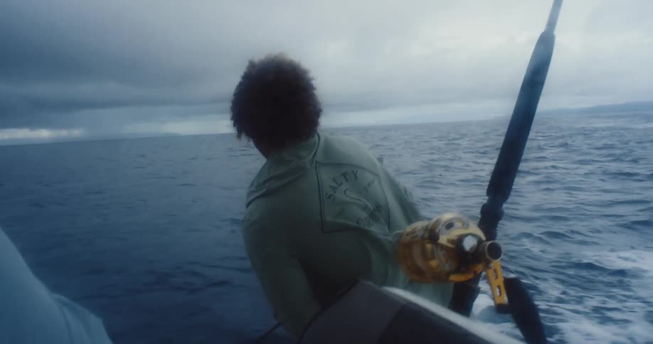 A man is fishing off a moving boat