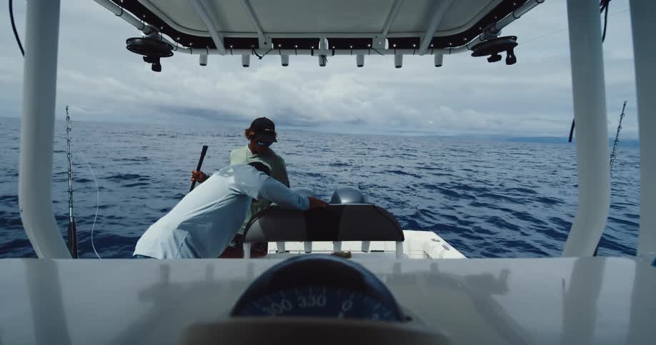 Two men pull up a fish on the boat