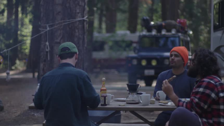 Campers gather at a picnic table to eat breakfast