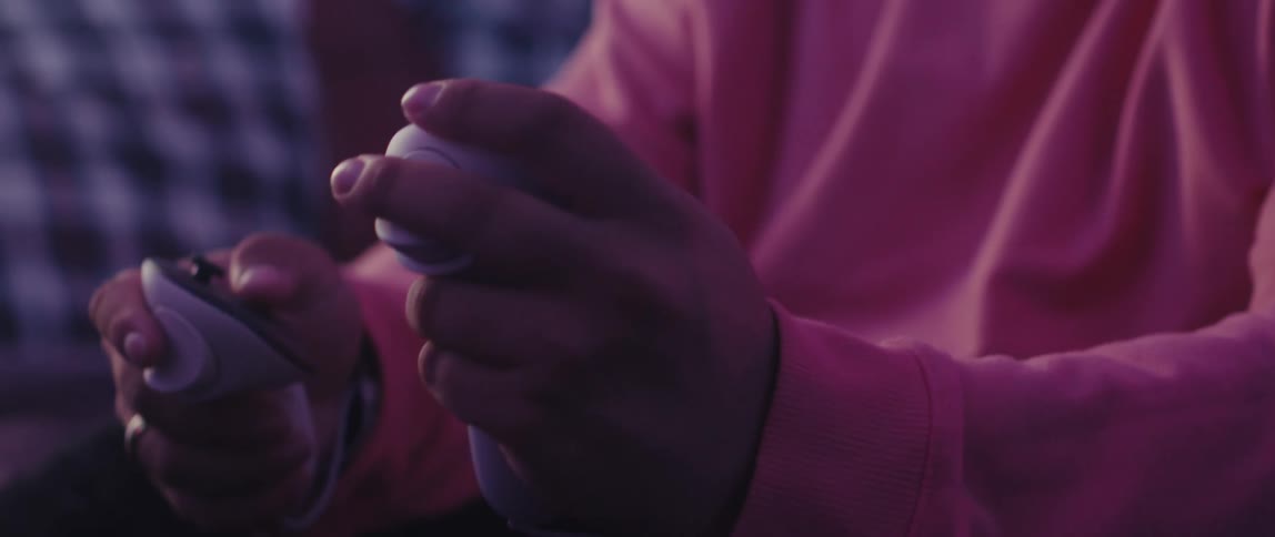 A person interacts with a vr controller in a room illuminated by pink lighting