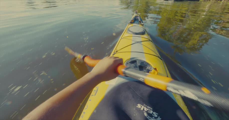 A person is rowing a kayak on a sunny day