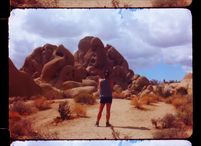 Woman in a desert environment with undergrowth and rocks