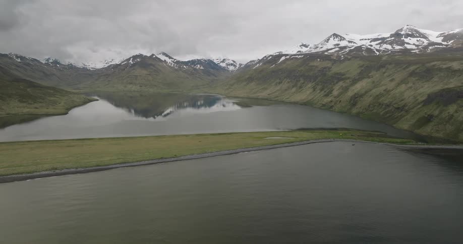 Aerial landscape of a lake surrounded by snowy mountains on a cloudy day