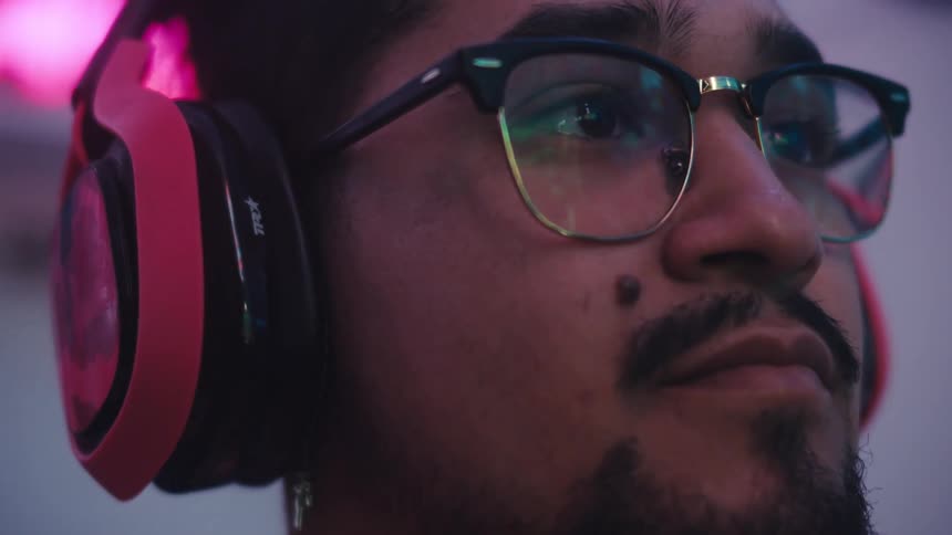 A man wearing headphones stares into the distance as he stands outside