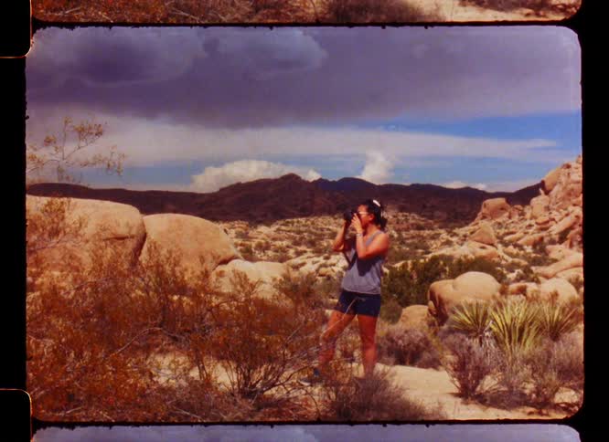 A woman stands in a desert landscape in the mountains to take a picture