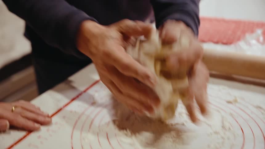 A man is in a kitchen kneading dough