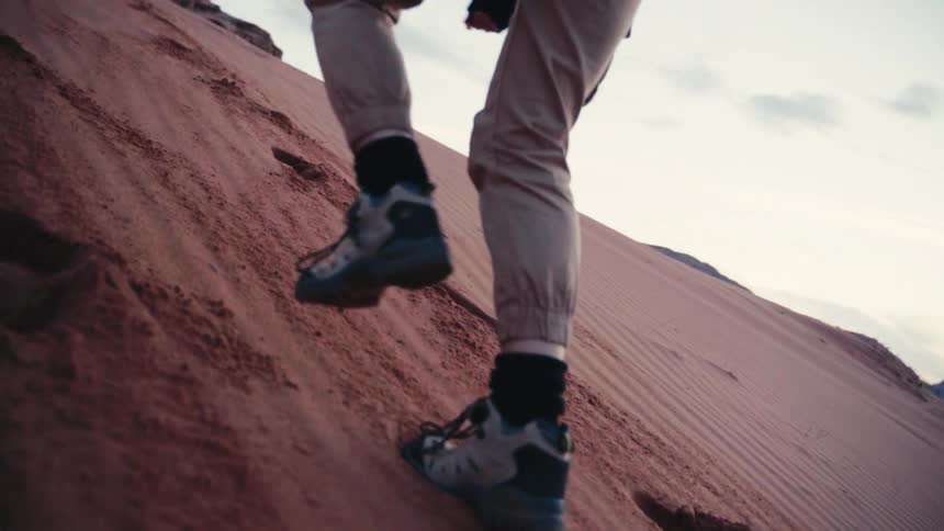 Legs of a person wearing hiking shoes walking up a deserted area