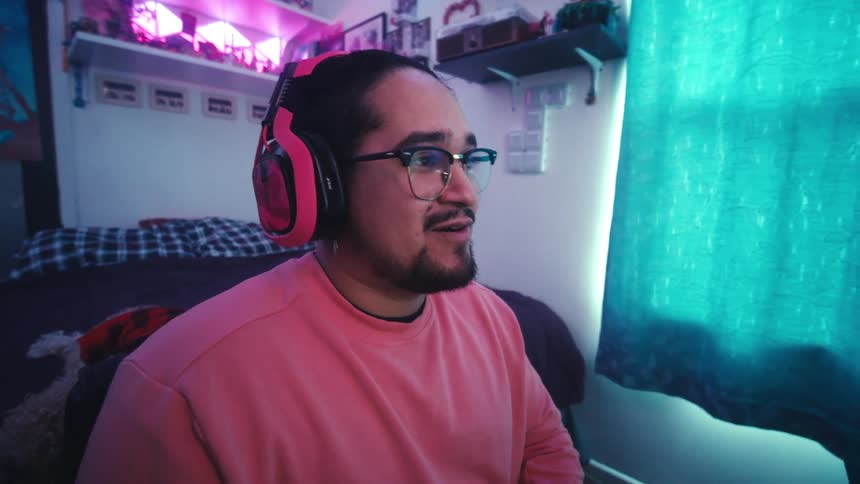 Man smiles while gaming in his bedroom