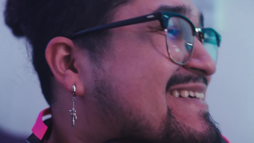 A man laughs and nods while he watches something