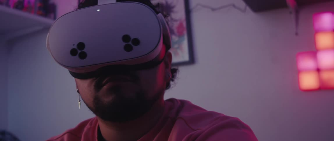 A person uses a meta quest pro vr headset in a pink lit room