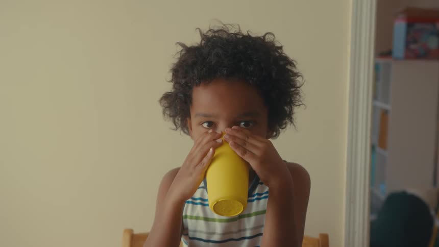 Child develops a milk mustache while drinking from a cup at home