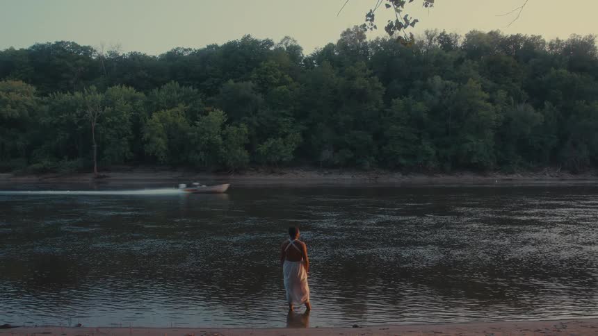 A clip of a person standing by the river shore
