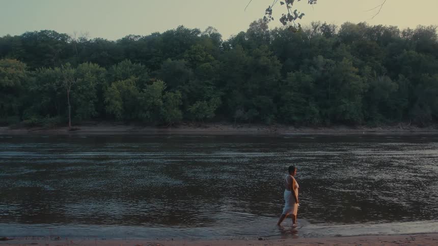 Person walking calmly along the edge of a river