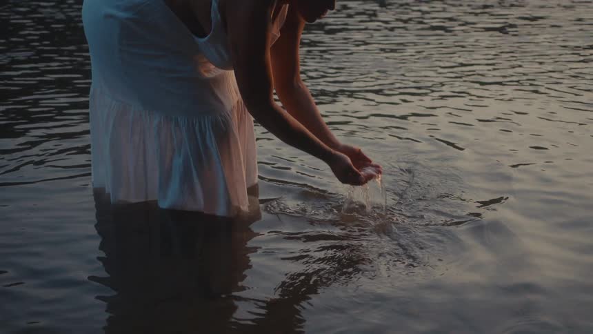 A clip of a woman deeping her hands into the river