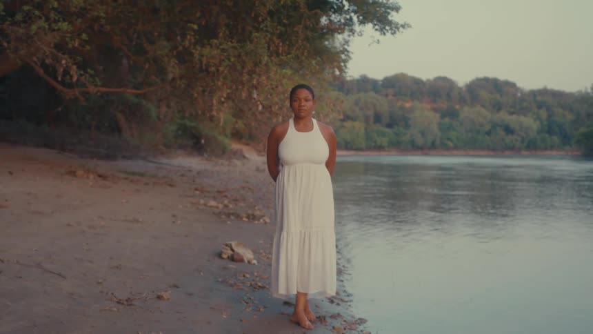 Woman in a long dress on the shore of a lake