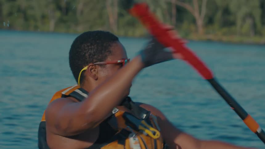 A woman is chewing as she kayaks on the lake