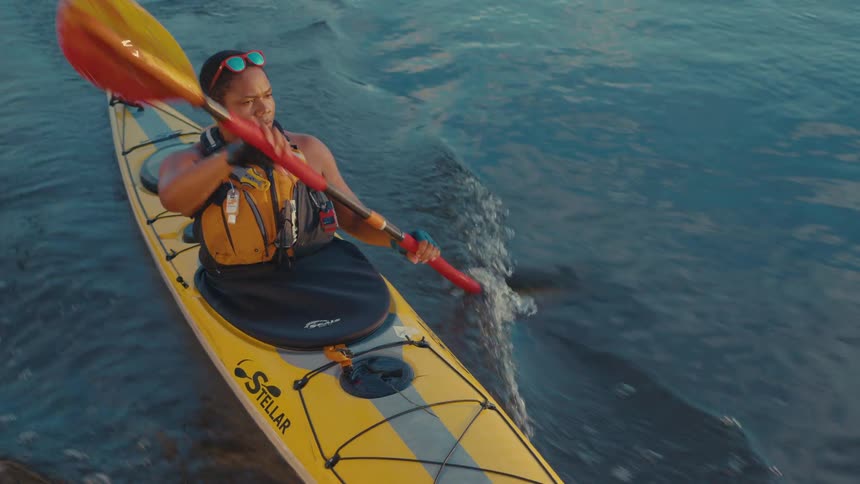 Woman paddling in a sit inside kayak on a lake