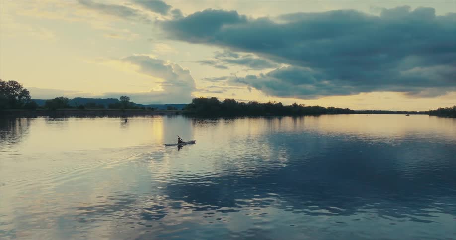 A person is kayaking at sunrise
