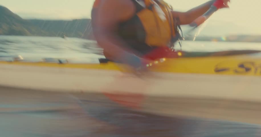 A person is kayaking on a calm body of water using a doublebladed paddle to propel a yellow kayak forward