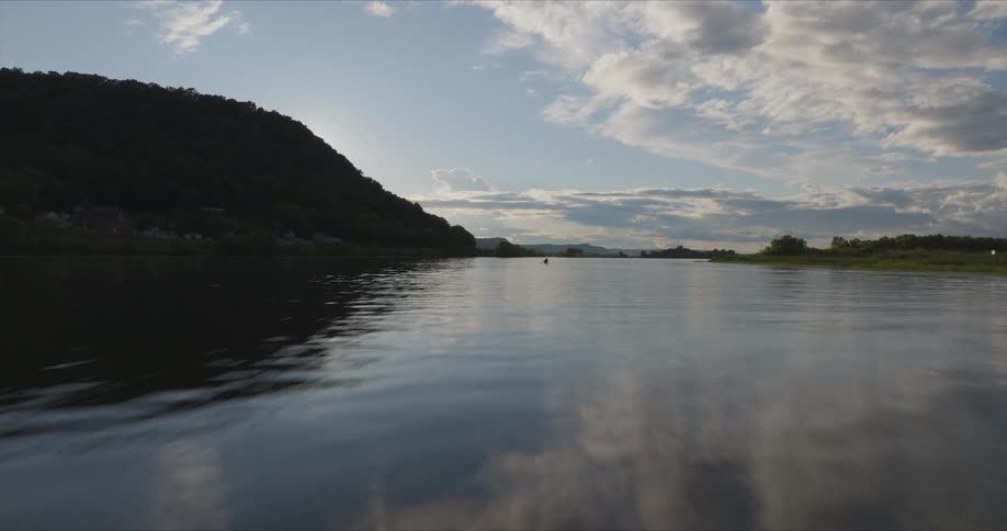 Kayak glides smoothly through the calm waters of a river at dusk