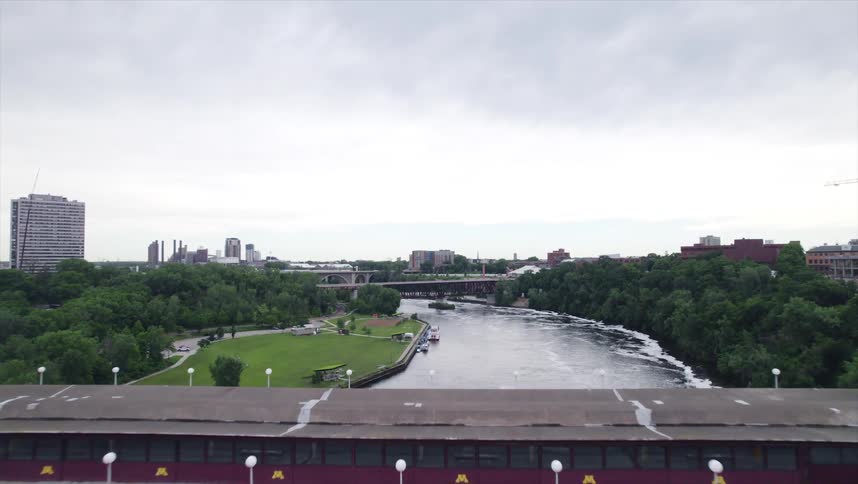 Vehicles cross a multi level bridge over the river near the city on a cloudy day
