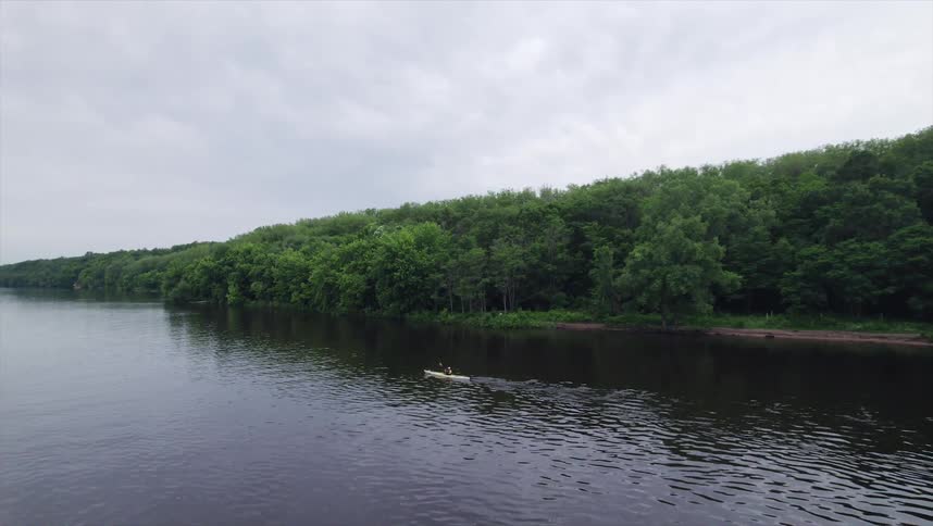 A person in a canoe in a lake quickly rows forward