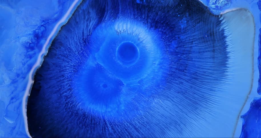 An abstract art piece that is a circle with liquid around it is entirely dark and light blue
