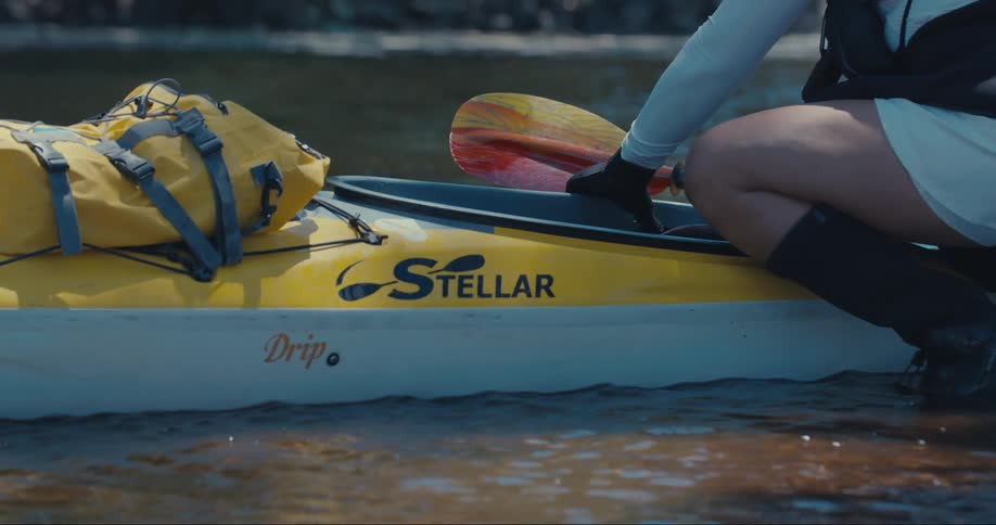 Person crouching next to a sport canoe