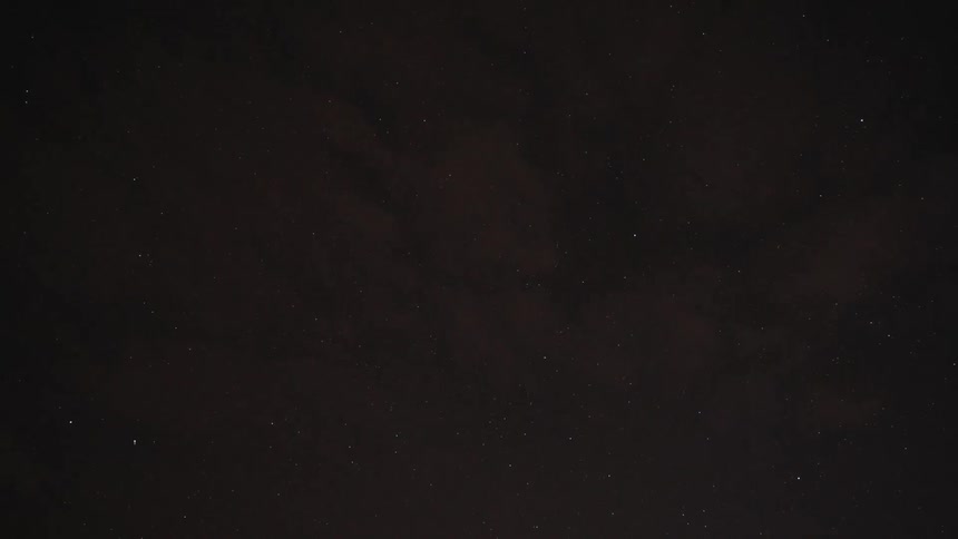 Thin clouds pass overhead partially obscuring the starry night sky