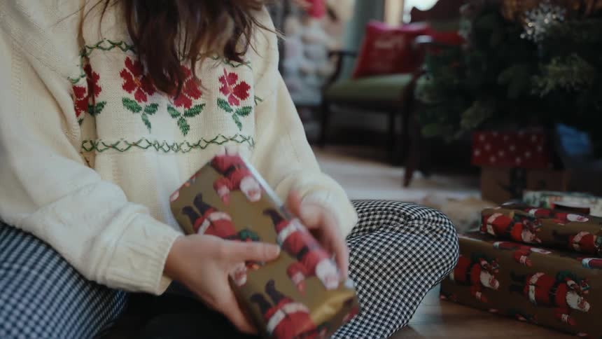 Hands of a woman finishing wrapping christmas presents