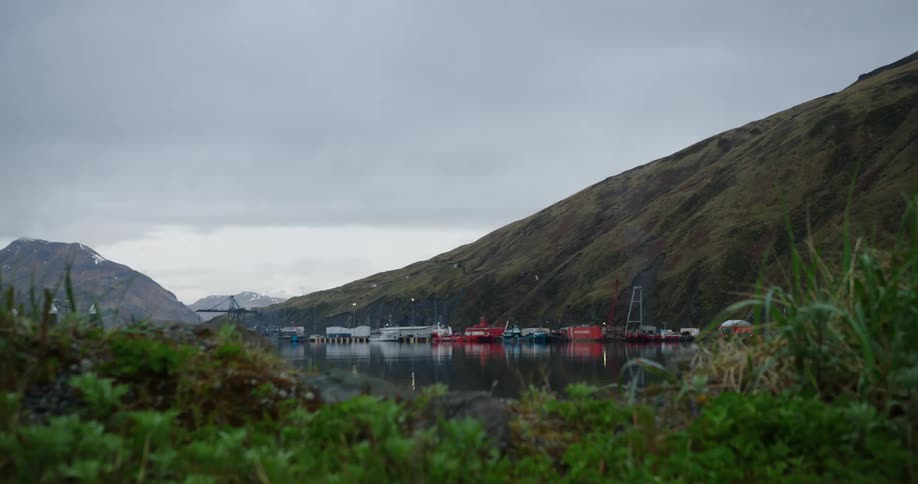 Cargo containers are on the small harbor by the mountain