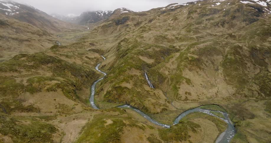 River winds through a mountain with snowy peaks