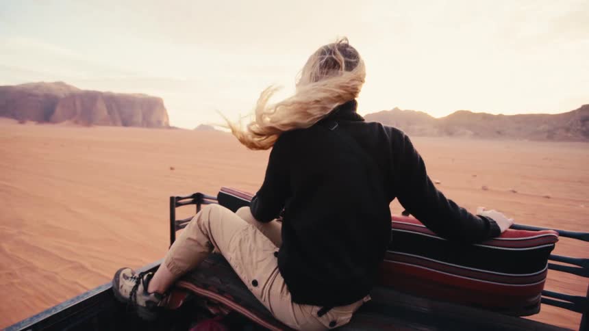 Long haired person sitting in a moving pickup truck through the desert