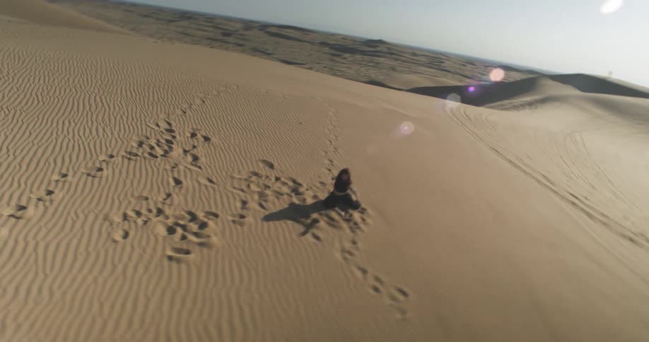 Woman in black dancing in a solo performance on a desert dune